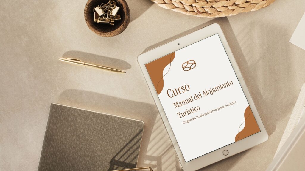 Tablet sobre un escritorio mostrando la portada del curso online "Manual del Alojamiento Turístico" de TurisUp.