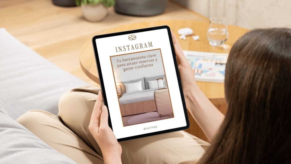 Mujer viendo en una tablet la portada del ebook de Turisup sobre Instagram para alojamientos turísticos.